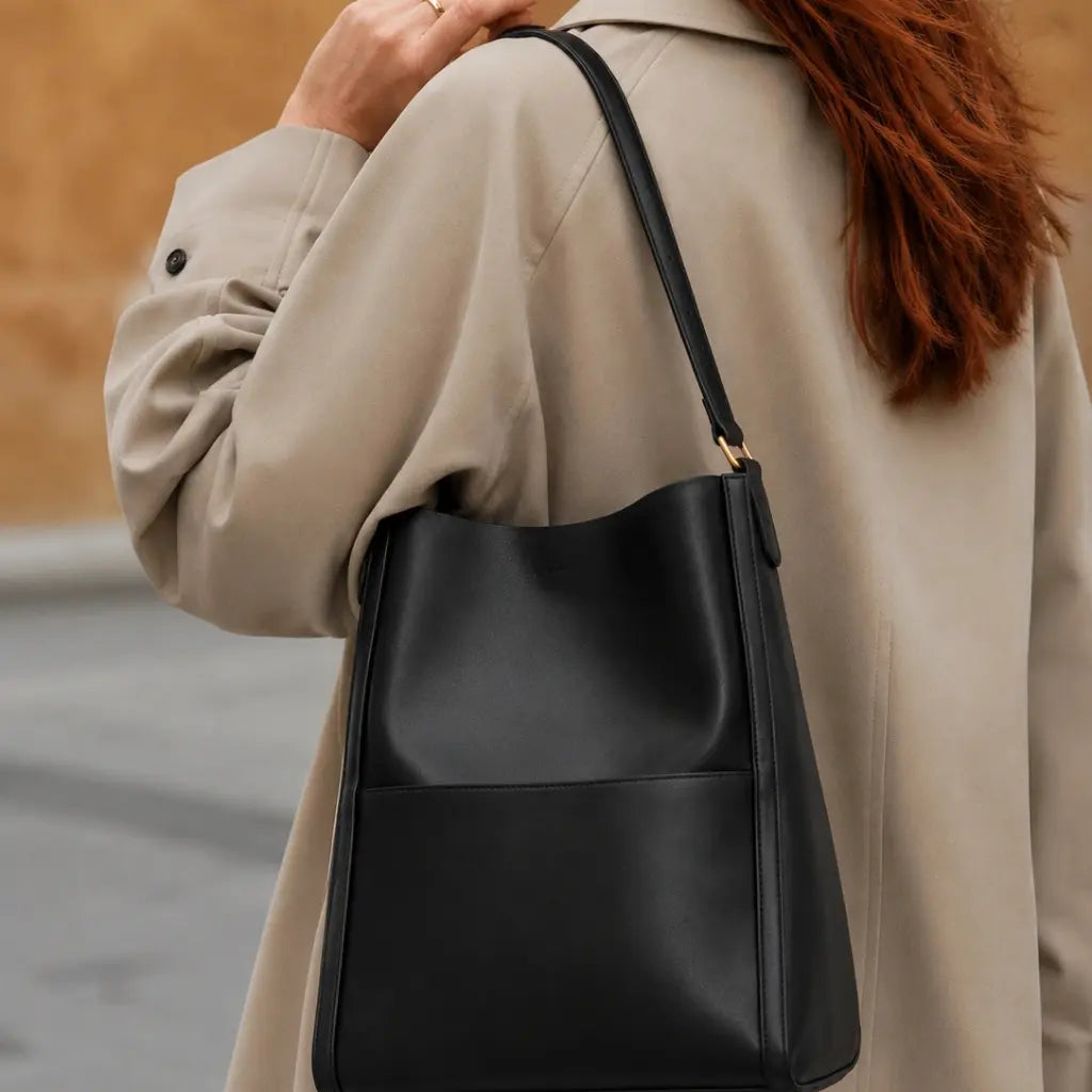 Bolsa de Ombro em Couro Eva Preta vista lateral evidenciando profundidade de 11cm e alça ajustável, fundo branco