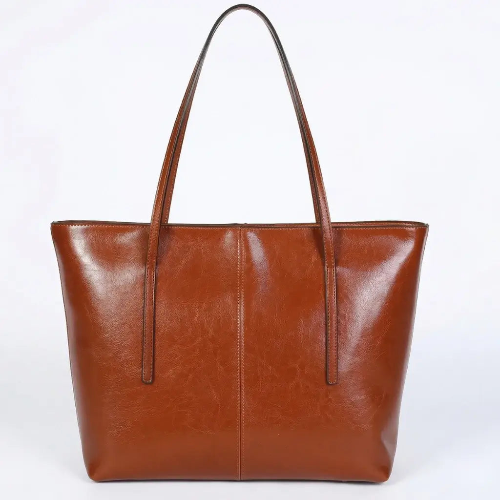 Bolsa feminina modelo Tote em couro legítimo marrom conhaque com acabamento brilhante, vista frontal em fundo branco isolado. 