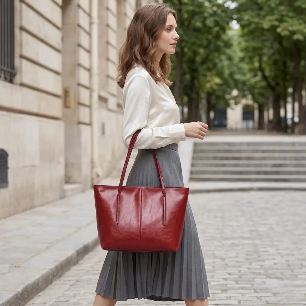 Bolsa tote feminina em couro vermelho sendo usada no ombro em vista lateral com look moderno