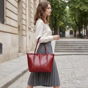 Bolsa tote feminina em couro vermelho sendo usada no ombro em vista lateral com look moderno