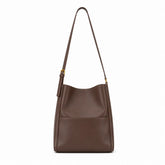 Modelo feminina usando a Bolsa de Ombro em Couro Eva Coffee no ombro em look casual com tom terroso e ferragens douradas