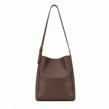 Modelo feminina usando a Bolsa de Ombro em Couro Eva Coffee no ombro em look casual com tom terroso e ferragens douradas