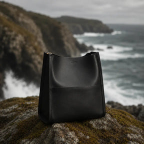 Detalhe em close da ferragem dourada e fivela da Bolsa de Ombro em Couro Eva Preta evidenciando acabamento premium