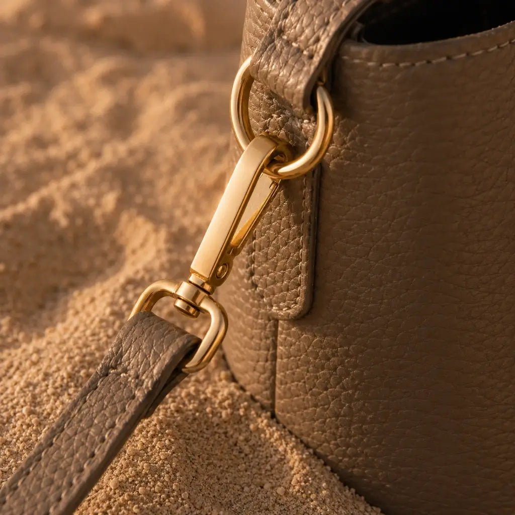 Detalhe da ferragem dourada da Bolsa de Mão Elara Areia em couro texturizado