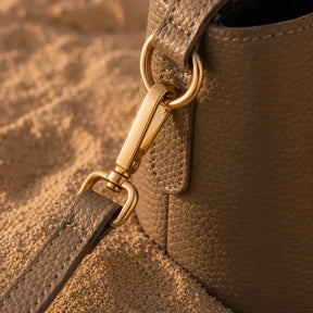 Detalhe da ferragem dourada da Bolsa de Mão Elara Areia em couro texturizado