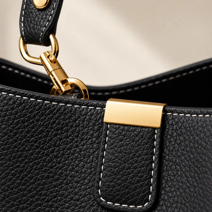 Detalhe do couro preto granulado, costuras e ferragens douradas da Bolsa Elara Preta