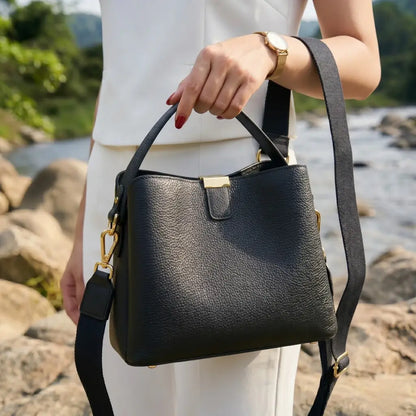 Mulher segurando bolsa feminina em couro preto com alça transversal, ideal para uso diário com estilo elegante e sofisticado
