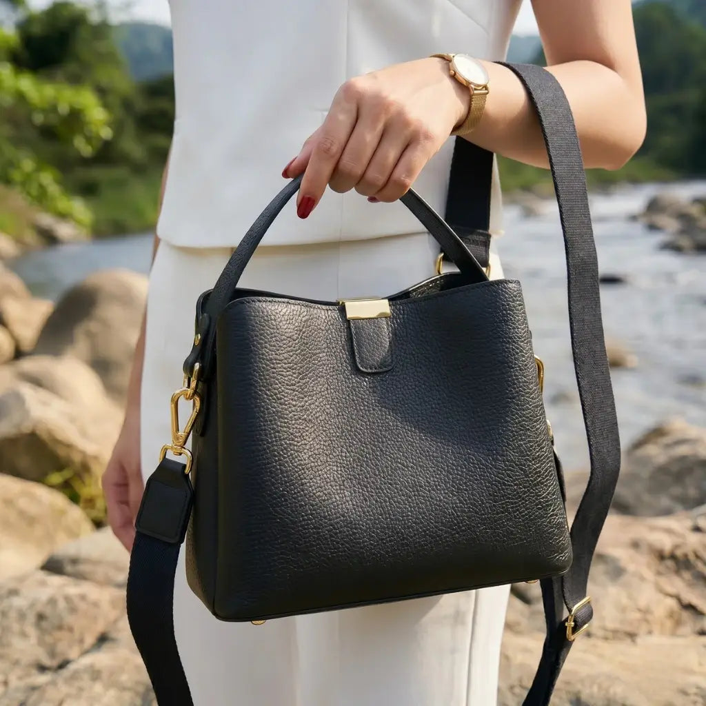 Mulher segurando bolsa feminina em couro preto com alça transversal, ideal para uso diário com estilo elegante e sofisticado