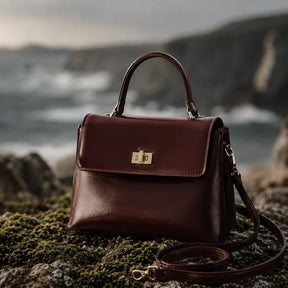 Bolsa Feminina em Couro Louise Bordô sendo usada por modelo em cenário costeiro sofisticado com estética de luxo silencioso.