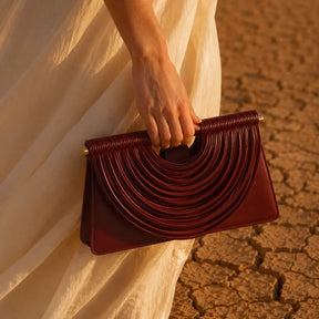 Bolsa feminina trançada borgonha Maya Nualle na mão detalhe trançado dourado look bege