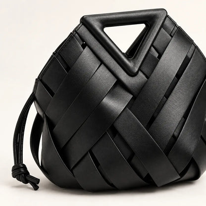 Detalhe da trama em couro preto e da alça triangular estruturada da Bolsa Iris