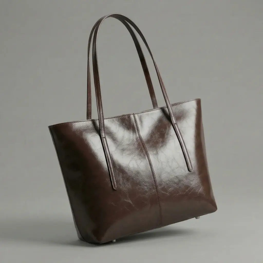 bolsa Tote Élise em couro marrom café no ombro. A imagem destaca o tamanho generoso da bolsa e como ela se ajusta confortavelmente ao corpo, ideal para um look de trabalho sofisticado."