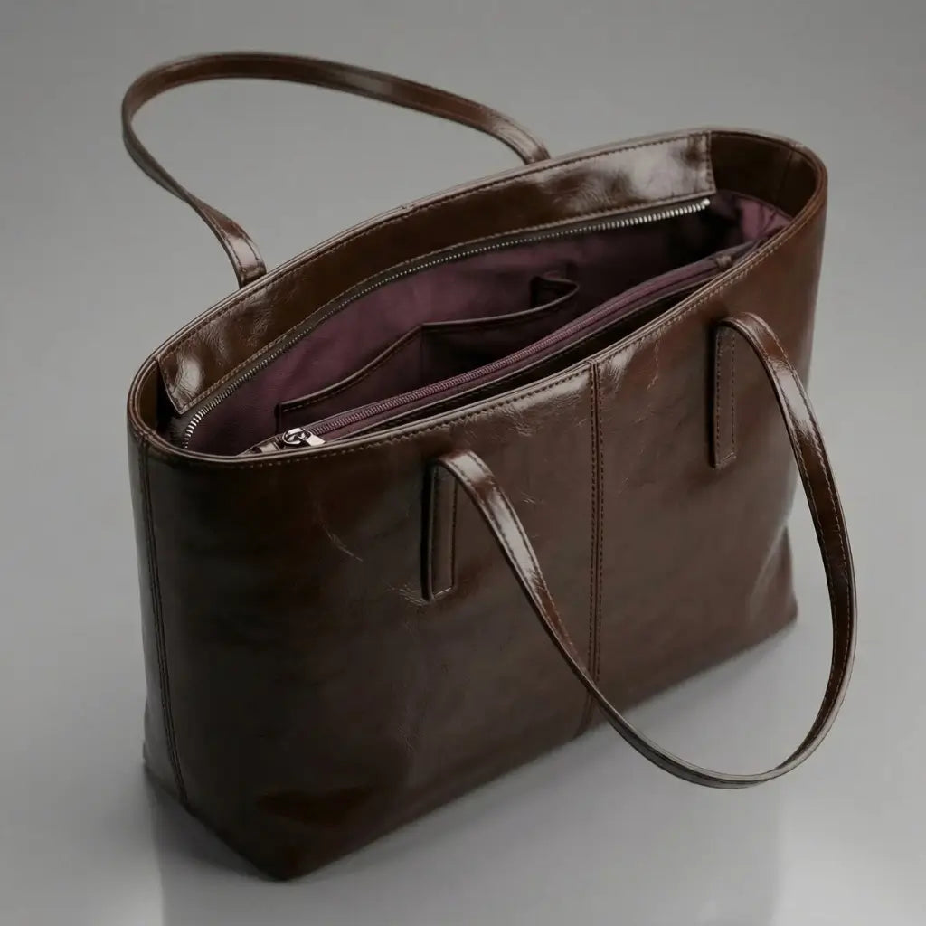 Interior da Bolsa Élise marrom aberta, mostrando divisórias internas, bolsos e forro vinho.