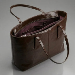 Interior da Bolsa Élise marrom aberta, mostrando divisórias internas, bolsos e forro vinho.