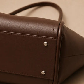 Detalhe da base da Bolsa Tote Zoé Coffee — pés metálicos prateados e costura reforçada